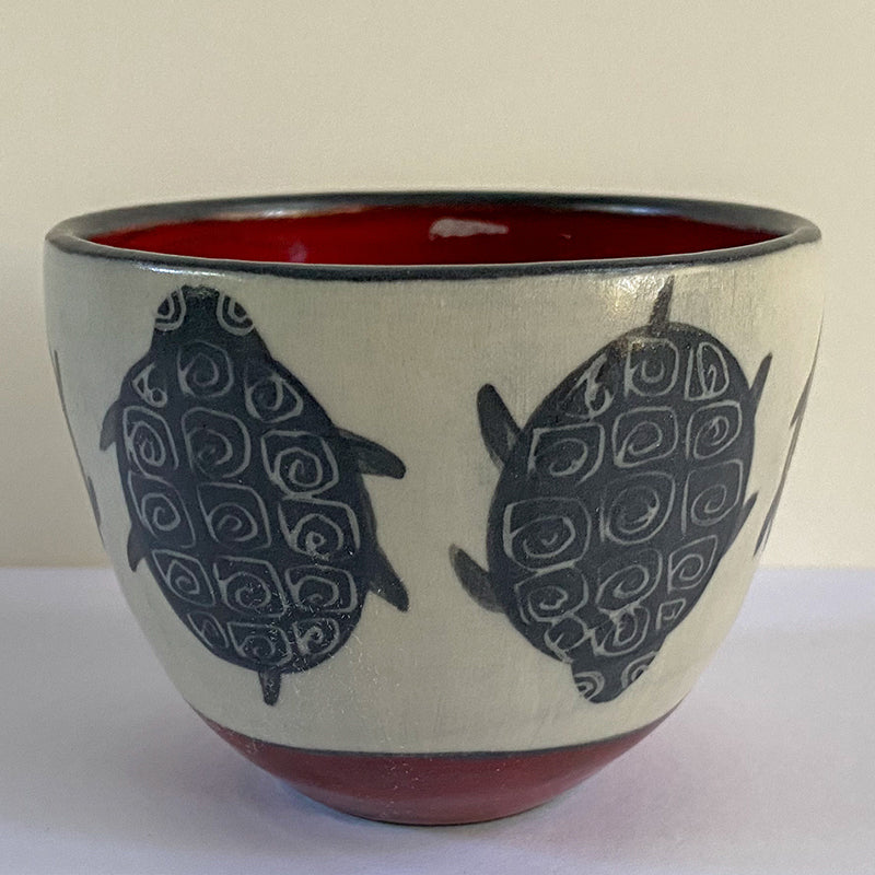 bowl with white on outside with black turtles and a red interior
